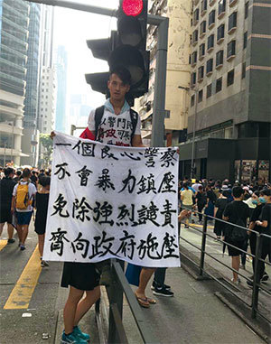 2019年7月21日，香港，民陣發起的反送中遊行隊伍中，有市民舉起「一個良心警察不會暴力鎮壓 免除強烈譴責 齊向政府施壓」的橫額。（蔡雯文／大紀元）